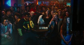 Movie still from “Hot Tub Time Machine” (2010), directed by Steve Pink – A group of people sitting around a table with drinks; Wide shot, High angle
