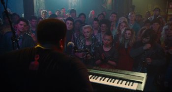 Movie still from “Hot Tub Time Machine” (2010), directed by Steve Pink – A crowd of people sitting and standing in front of a piano; Wide shot, High angle