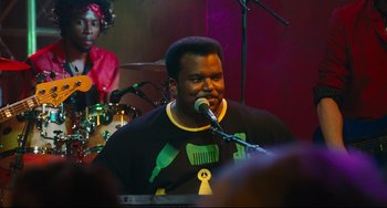 Movie still from “Hot Tub Time Machine” (2010), directed by Steve Pink – A man is singing into a microphone at an event; Medium shot, Over the shoulder angle