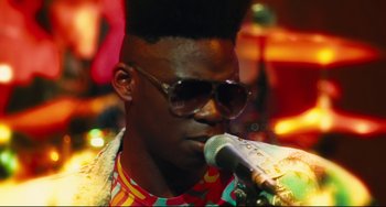 Movie still from “Hot Tub Time Machine” (2010), directed by Steve Pink – A man with sunglasses and a mohawk is singing into a microphone; Close Up shot, Low angle