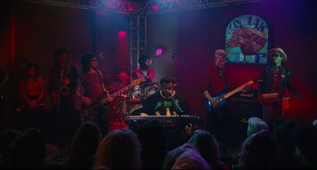 Movie still from “Hot Tub Time Machine” (2010), directed by Steve Pink – A group of people on a stage with instruments; Wide shot, Low angle