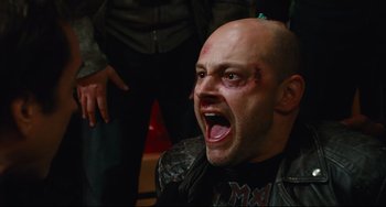 Movie still from “Hot Tub Time Machine” (2010), directed by Steve Pink – A man with a shaved head and a black shirt is screaming with his mouth wide open; Close Up shot, High angle