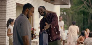 Movie still from “Black Mirror” (2011), created by Charlie Brooker – Two men standing next to each other and one of them is holding a bag; Medium shot, Over the shoulder angle