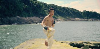 Movie still from “Black Mirror” (2011), created by Charlie Brooker – A young man is kicking around a rock by the water; Wide shot, Low angle