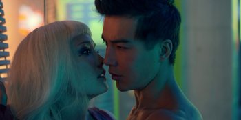 Movie still from “Black Mirror” (2011), created by Charlie Brooker – A man and a woman kissing in a room lit by a neon light; Close Up shot, Over the shoulder angle