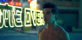 Movie still from “Black Mirror” (2011), created by Charlie Brooker – A young man is standing in front of a neon sign; Close Up shot, Over the shoulder angle