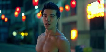 A shirtless man standing in front of street lights at night