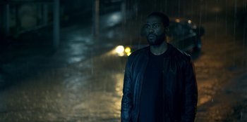 Movie still from “Black Mirror” (2011), created by Charlie Brooker – A man standing in the rain in the dark; Medium shot, Low angle