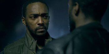 Movie still from “Black Mirror” (2011), created by Charlie Brooker – A man looking at another man in a leather jacket; Close Up shot, Over the shoulder angle