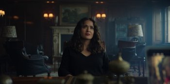 Movie still from “Black Mirror” (2011), created by Charlie Brooker – A woman sitting at a table in a room; Medium shot, Low angle
