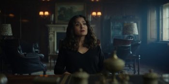 Movie still from “Black Mirror” (2011), created by Charlie Brooker – A woman sitting at a dining room table; Medium shot, Low angle