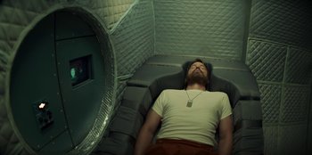 Movie still from “Black Mirror” (2011), created by Charlie Brooker – A man laying on a bed in a room with a mirror; Medium shot, Overhead angle