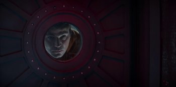Movie still from “Black Mirror” (2011), created by Charlie Brooker – A man looking into a mirror in a room with red walls; Close Up shot, Low angle
