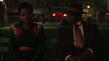 Movie still from “A League of Their Own” (2022), created by Abbi Jacobson – A man and a woman are sitting on a park bench; Medium shot, Over the shoulder angle