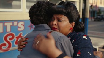 Movie still from “A League of Their Own” (2022), created by Abbi Jacobson – A woman is hugging a man in front of a building; Close Up shot, Over the shoulder angle