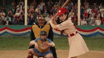 Movie still from “A League of Their Own” (2022), created by Abbi Jacobson – A woman is swinging a baseball bat at a game; Medium shot, Over the shoulder angle