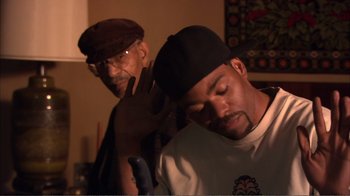 Movie still from “How High” (2001), directed by Jesse Dylan – Two men in a room with one of the men brushing the other's hair; Medium shot, Over the shoulder angle