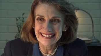 Movie still from “How High” (2001), directed by Jesse Dylan – An older woman smiling for the camera with pearls around her neck; Close Up shot, Over the shoulder angle