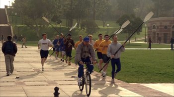 Movie still from “How High” (2001), directed by Jesse Dylan – A group of men holding oars while riding bikes; Wide shot, High angle