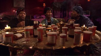 Movie still from “How High” (2001), directed by Jesse Dylan – A group of people sitting around a table with medicine bottles; Medium shot, High angle