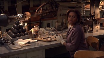 Movie still from “How High” (2001), directed by Jesse Dylan – A woman sitting at a table in a lab; Medium shot, High angle