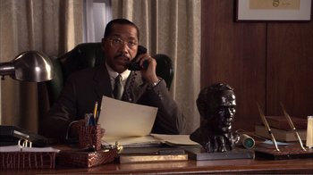 Movie still from “How High” (2001), directed by Jesse Dylan – A man sitting at a desk talking on the phone; Medium shot, High angle