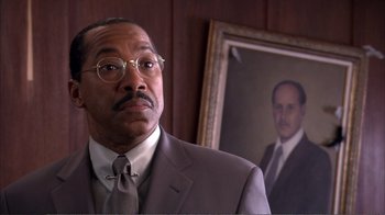 Movie still from “How High” (2001), directed by Jesse Dylan – A man in a suit and tie standing next to a painting; Close Up shot, Low angle