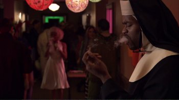 Movie still from “How High” (2001), directed by Jesse Dylan – A nun smoking a cigarette in front of a crowd; Medium shot, Over the shoulder angle