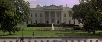 Movie still from “In the Line of Fire” (1993), directed by Wolfgang Petersen – A man walking on a sidewalk near a fountain; Extreme Wide shot, Low angle