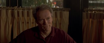 Movie still from “In the Line of Fire” (1993), directed by Wolfgang Petersen – An older man in a red shirt is looking at the camera; Close Up shot, Over the shoulder angle
