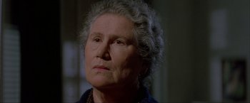 Movie still from “In the Line of Fire” (1993), directed by Wolfgang Petersen – An older woman with a gray hair looking at the camera; Close Up shot, Over the shoulder angle