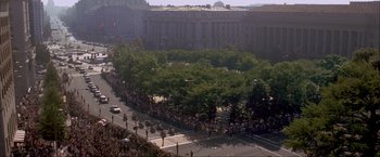 Movie still from “In the Line of Fire” (1993), directed by Wolfgang Petersen – A large crowd of people are gathered on the street; Extreme Wide shot, High angle
