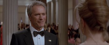 Movie still from “In the Line of Fire” (1993), directed by Wolfgang Petersen – A man in a suit and bow tie standing in front of a crowd of onlookers; Close Up shot, Low angle