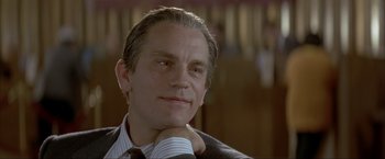 Movie still from “In the Line of Fire” (1993), directed by Wolfgang Petersen – A man that is sitting down with his hand under his chin; Close Up shot, Low angle