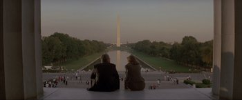 Movie still from “In the Line of Fire” (1993), directed by Wolfgang Petersen – Two people sitting on a ledge looking at the washington monument; Extreme Wide shot, Over the shoulder angle