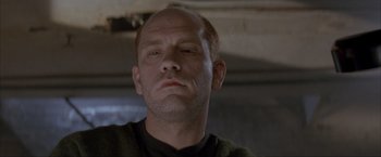 Movie still from “In the Line of Fire” (1993), directed by Wolfgang Petersen – A man with a bald head is looking at the camera; Close Up shot, Low angle