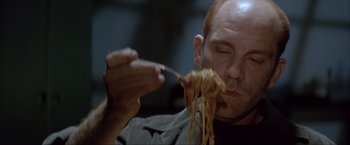 Movie still from “In the Line of Fire” (1993), directed by Wolfgang Petersen – A man is eating some noodles with a fork; Close Up shot, Low angle