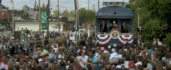 Movie still from “In the Line of Fire” (1993), directed by Wolfgang Petersen – A crowd of people gathered in front of a train; Extreme Wide shot, High angle
