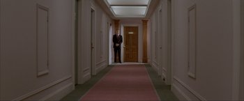 Movie still from “In the Line of Fire” (1993), directed by Wolfgang Petersen – A man in a suit standing in the hallway of a building; Wide shot, Low angle