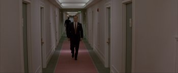 Movie still from “In the Line of Fire” (1993), directed by Wolfgang Petersen – A man in a suit walking down a long hallway; Wide shot, Low angle