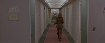 Movie still from “In the Line of Fire” (1993), directed by Wolfgang Petersen – A woman walking down a long hallway in a hotel room; Wide shot, High angle