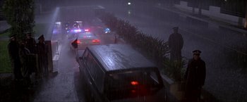 Movie still from “In the Line of Fire” (1993), directed by Wolfgang Petersen – A van is driving down a street in the rain; Extreme Wide shot, High angle