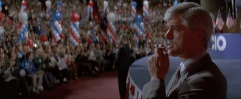 Movie still from “In the Line of Fire” (1993), directed by Wolfgang Petersen – A man in a suit and tie holding a cell phone to his ear; Medium shot, Low angle