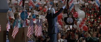 Movie still from “In the Line of Fire” (1993), directed by Wolfgang Petersen – A man in a suit is waving at a crowd; Wide shot, High angle