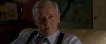 Movie still from “In the Line of Fire” (1993), directed by Wolfgang Petersen – An older man wearing a neck tie sitting down; Close Up shot, Over the shoulder angle