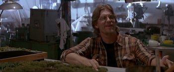 Movie still from “In the Line of Fire” (1993), directed by Wolfgang Petersen – A man sitting at a table in front of a window; Medium shot, Low angle