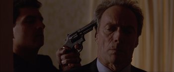 Movie still from “In the Line of Fire” (1993), directed by Wolfgang Petersen – A man holding a gun up to his head; Close Up shot, High angle
