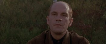 Movie still from “In the Line of Fire” (1993), directed by Wolfgang Petersen – A man with a bald head is looking at the camera; Close Up shot, Low angle