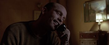 Movie still from “In the Line of Fire” (1993), directed by Wolfgang Petersen – A man talking on a phone while sitting in a room; Close Up shot, Low angle