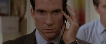 Movie still from “In the Line of Fire” (1993), directed by Wolfgang Petersen – A person wearing a suit and tie; Close Up shot, High angle
